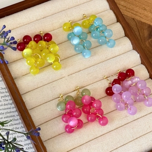 Détail de quatre paires de boucles d'oreilles grappes de raisin en résine sur velours