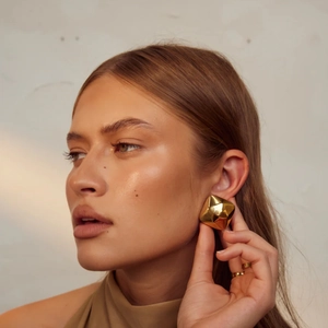 Detailed close-up of 18k gold-plated square geometric stud earrings on a model
