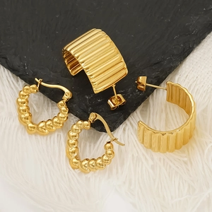 Golden heart bead earrings and striped C-shape studs set on elegant black and white decor