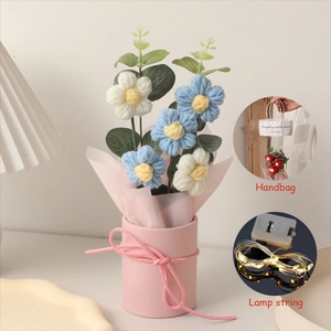 Close-up of knitted floral bouquet with LED string lights and pink gift carry bag
