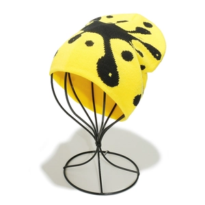 Detail of yellow ribbed knit beanie with black butterfly jacquard pattern on display stand