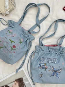 Light blue denim drawstring tote bag with floral embroidery and red checkered lining