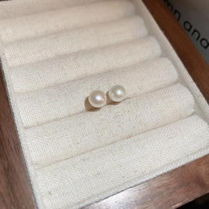 Close-up of elegant white pearls on soft velvet lining for minimalist silver stud earrings