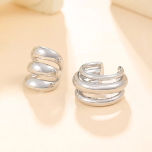Macro view of silver triple-layered polished ear cuffs showing sleek metallic luster