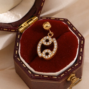 Detailed view of Cancer zodiac pendant with white zircon inlays on a vintage wooden box