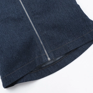 Detailed macro view of dark blue denim fabric with silver zipper and orange stitching