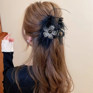 Détail d'une pince à cheveux de luxe ornée de strass brillants et de plumes noires