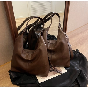 Detail view of large dark brown soft leather tote bag reflected in a wooden frame mirror