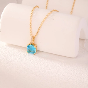 Close-up of square light blue gemstone necklace with gold chain on display stand