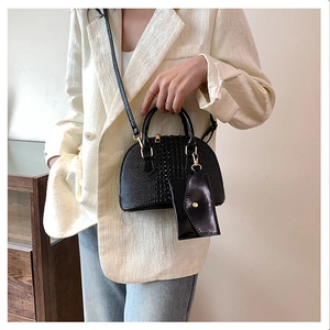 Detail view of black crocodile pattern shell bag with metal hardware and mini pouch