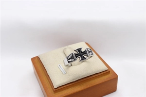 Detail of vintage steel ring featuring black enamel cross and engraved side patterns