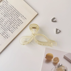Détail d'une pince à cheveux beige avec nœud et boucles d'oreilles géométriques
