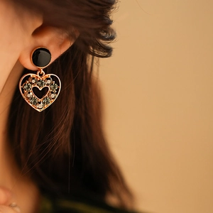 Gros plan de boucles d'oreilles cœur vintage serties de strass gris sur modèle