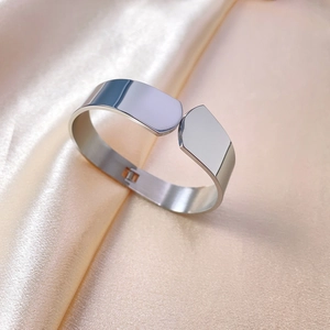 Minimalist silver titanium steel bangle with polished finish on beige silk background
