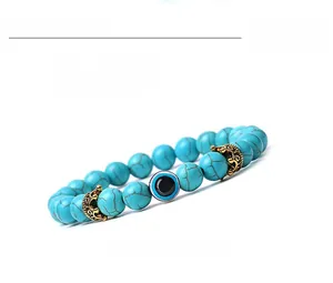 Detail view of 8mm blue turquoise beads with evil eye charm and golden crown spacers