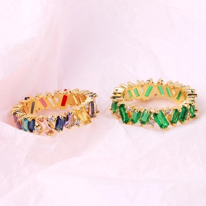 Macro detail of 18K gold plated rings featuring baguette-cut colorful and green zircons