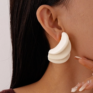 Close-up of white matte resin earrings with a triple-layered geometric shell design