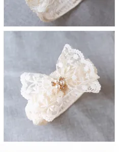 Detail of off-white lace baby headband featuring a bow with pearl and rhinestone inlay