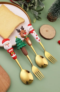 Dettaglio di quattro cucchiai e forchette natalizi dorati con figurine festive