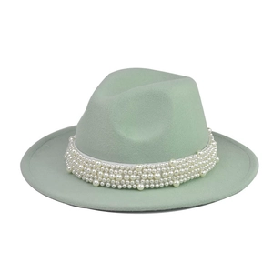 Detalle de sombrero fedora verde menta con cinta de satén blanco y adornos de perlas