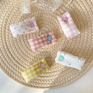 Flat lay of colorful floral fabric cable clips with heart buttons on a straw tray
