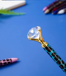 Detailed close-up of blue leopard print metal pen with a large sparkling crystal diamond top