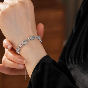 Macro detail of silver bracelet featuring light blue oval stones and zircon flower accents