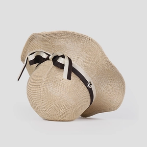 Summer wide brim straw sun hat with wavy edges and decorative bow accent for women