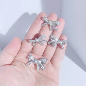 Close-up of four silver bow rings with pavé diamonds on fingers in bright natural light