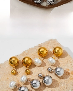 Detailed display of pearl and metallic ball stud earrings on a textured stone surface