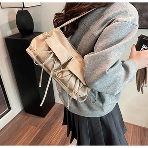 Detail of beige bow-knot bowling bag with shiny synthetic leather and ruffled design