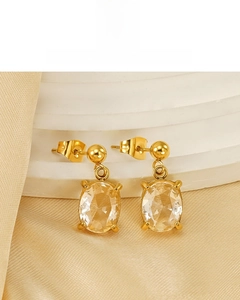 Détail de boucles d'oreilles plaquées or 18 carats avec zircone ovale et serti quatre griffes