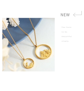Detail of matte gold dual ring pendants with mountain relief on minimalist background
