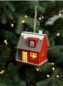 Detail of wooden Christmas cottage hanging on a tree with warm LED lights