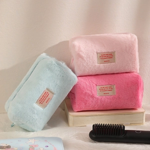 Three plush makeup bags in blue and pink colors with rectangular text labels