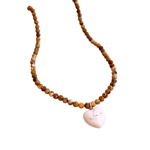 Vintage style beaded necklace featuring earth-tone stones and a heart Saturn pendant
