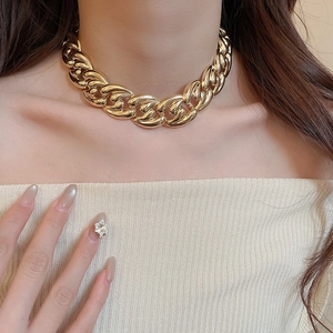 Close-up of a model wearing a thick golden metal chain necklace with a glossy finish