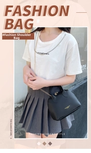 Chic black PU leather handbag with dual handles and chain strap worn by a model