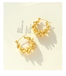 Macro detail of French style twisted C-shape earrings with a polished gold-plated finish