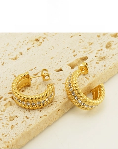 Detailed close-up of gold rope-textured C-shape earrings with clear sparkling zircon stones