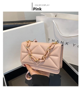 Detailed close-up of pink quilted crossbody bag with gold chain and wide shoulder strap
