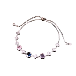 Elegant silver bracelet with colorful zircons and clover charm on white background