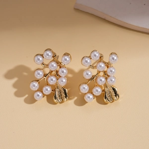 Detail of vintage gold flower earrings with elegant white pearls on beige background