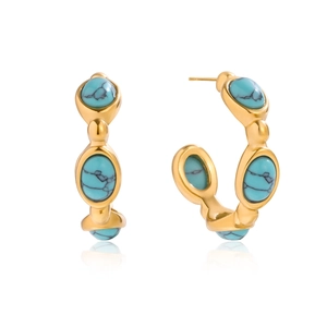 Detailed close-up of C-shaped gold earrings set with turquoise stones and marble texture