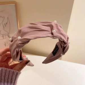 Dettaglio del cerchietto plissettato rosa con perle eleganti ed etichetta fatta a mano inclusa