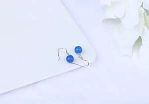 Detail of blue agate bead earrings on a white floral background with silver hooks