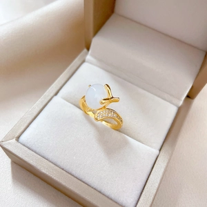 Adjustable gold ring with white jade fox and zircon accents in a beige jewelry box