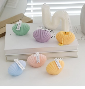 Artistic shell-shaped candles in pastel colors arranged on a white decorative table