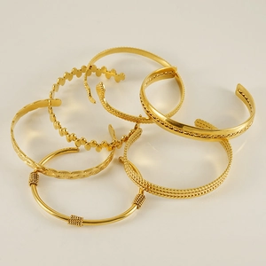 Stack of vintage gold titanium steel C-shape open bangles with woven and beaded textures