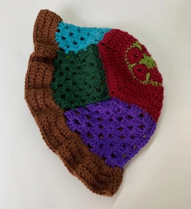 Detail of colorful handmade crochet bucket hat with intricate knit patterns and floral brim